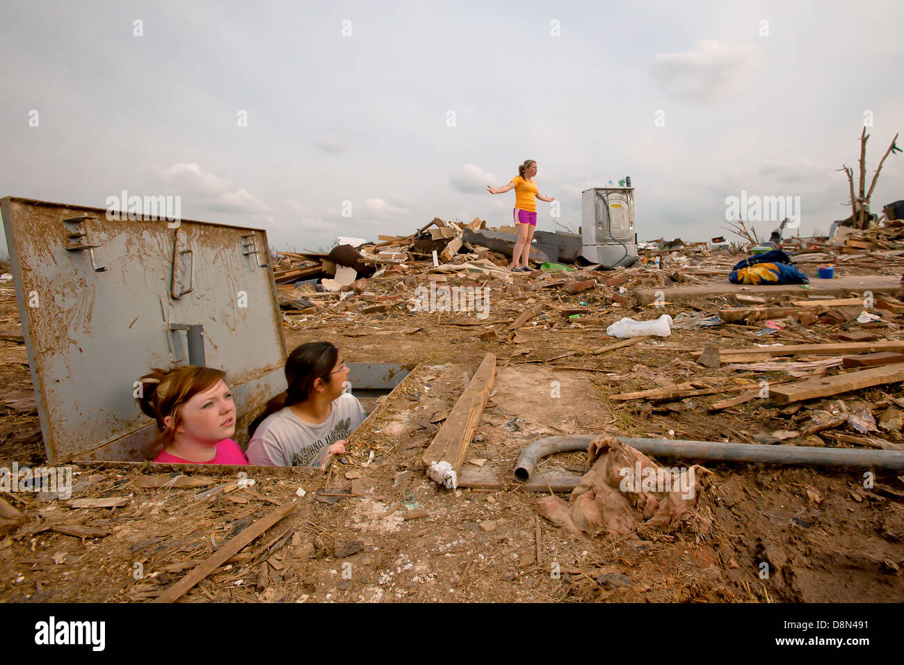 Young girls view the remains of their home from where they hid in a storm shelter in the aftermath of an EF-5 tornado May 24, 2013 in Moore, Oklahoma. The massive storm with winds exceeding 200 miles per hour tore through the Oklahoma City suburb May 20, 2013, killing at least 24 people, injuring more than 230 and displacing thousands. Stock Photo