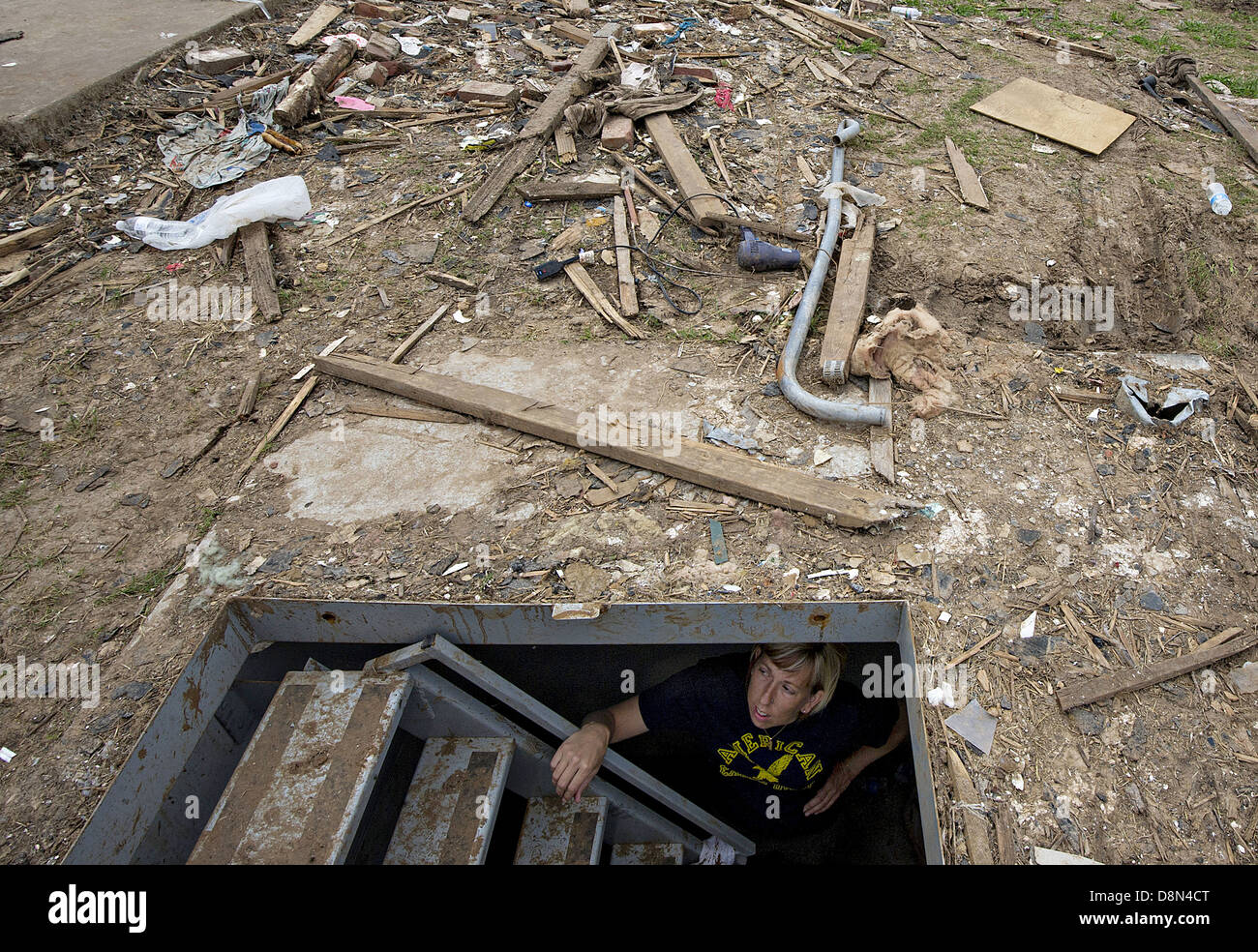 Christie England looks out from the storm shelter that saved her life in the remains of her former home in the aftermath of an EF-5 tornado May 27, 2013 in Moore, Oklahoma. The massive storm with winds exceeding 200 miles per hour tore through the Oklahoma City suburb May 20, 2013, killing at least 24 people, injuring more than 230 and displacing thousands. Stock Photo