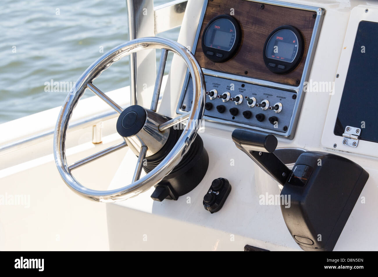 A chrome and wood cockpit of a motorboat including wheel, tach and throttle Stock Photo