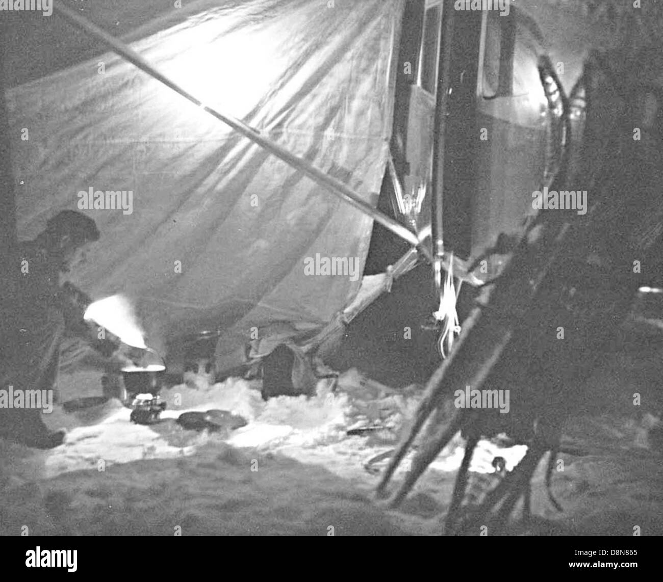 Man bending over cook stove outside plane at night tarp provides protection  Stock Photo - Alamy