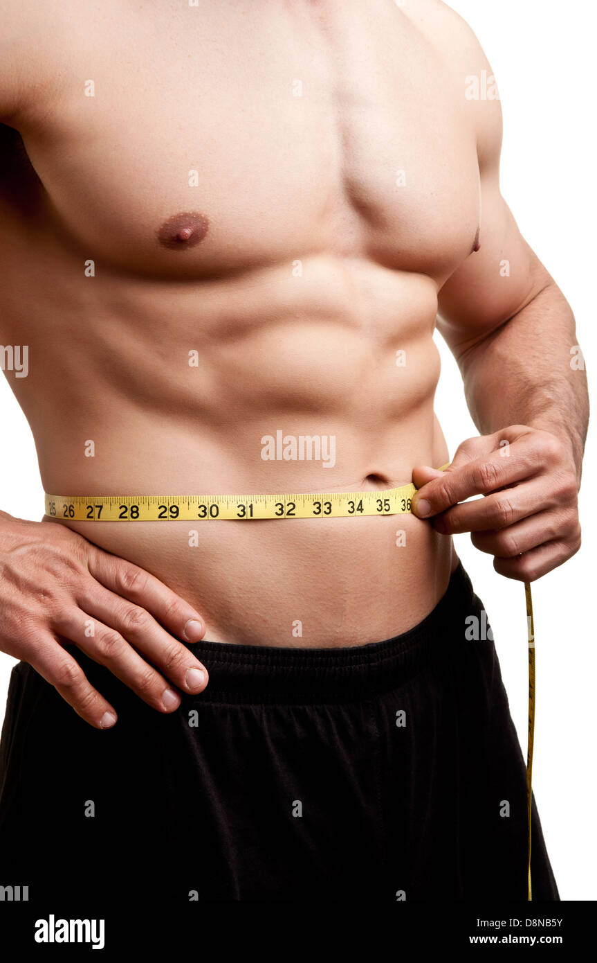 Fit man measuring his waist after a workout in the gym, isolated in a white background Stock Photo