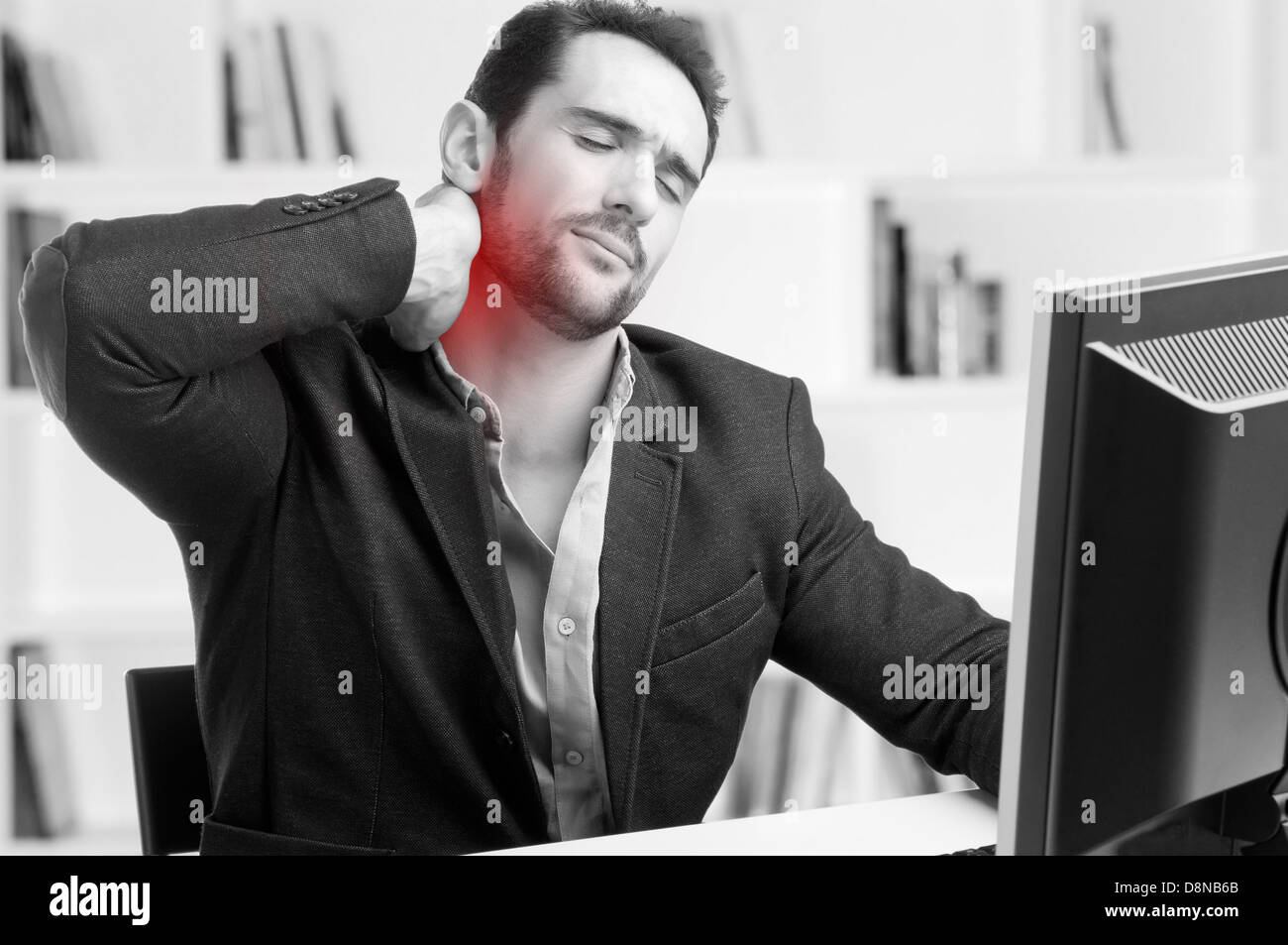 Casual businessman sitting in a desk with pain in his neck, black and white, red dot around painful area Stock Photo