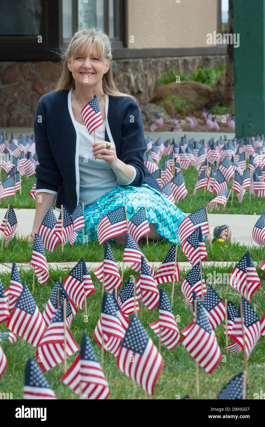 Woman smiling at camera while holding a United States flag and sitting ...
