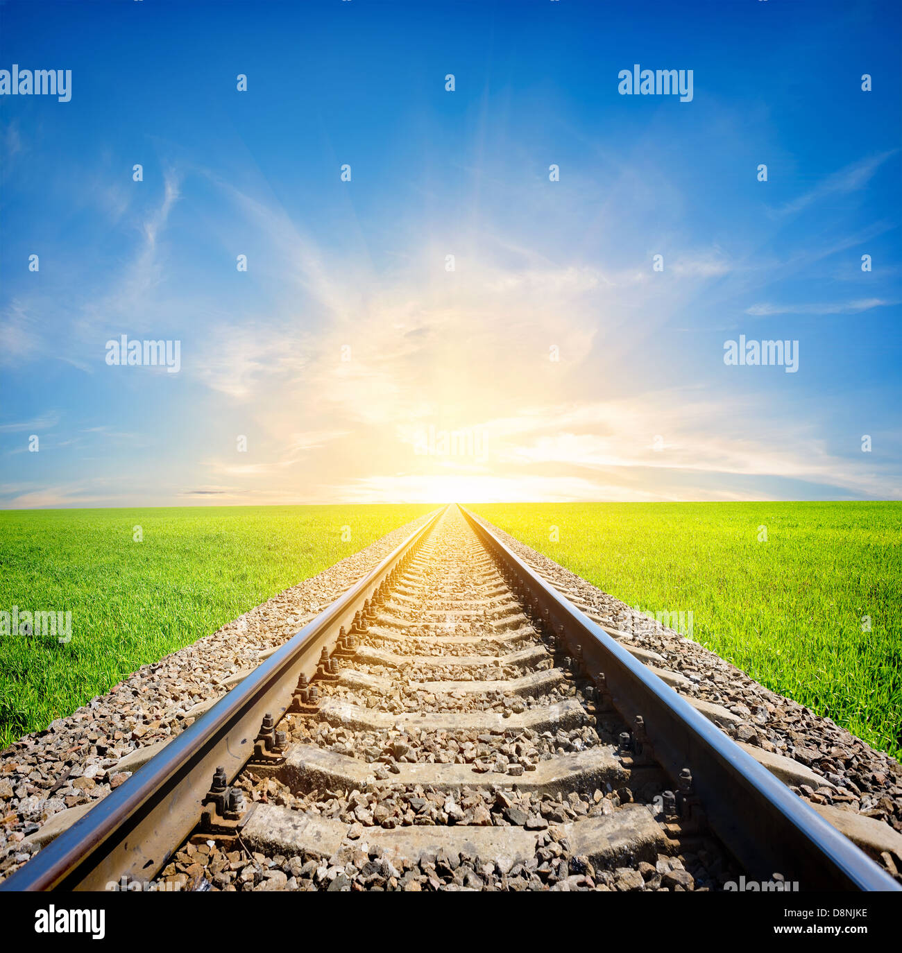 Railway to the sun through green field Stock Photo