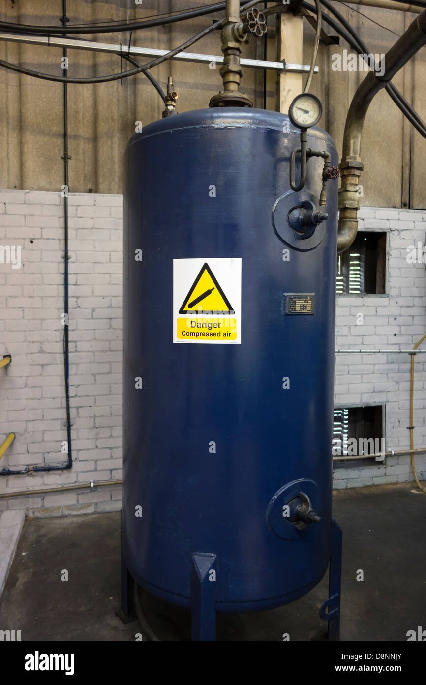Compressed air storage cylinder or vessel with warning sign. Stock Photo