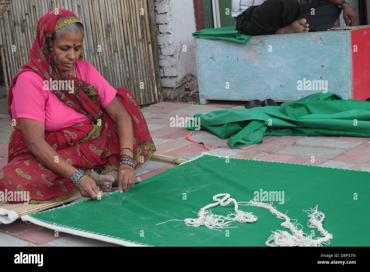 A woman gives finishing touches to a bamboo curtain in Old Delhi, India. Stock Photo