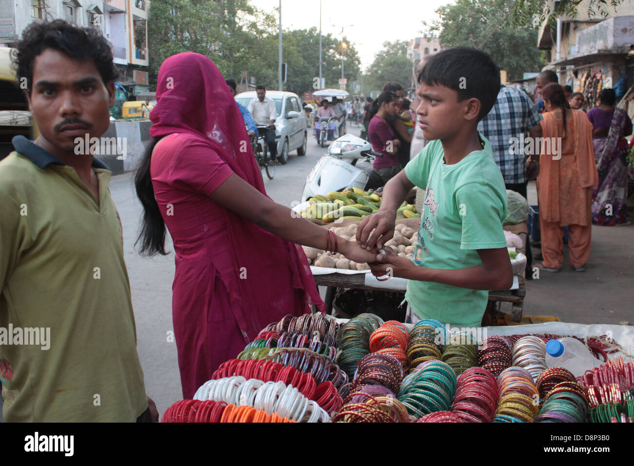 A pregnant woman tries on bangles with help from a bangle-seller in Old Delhi, India. Stock Photo