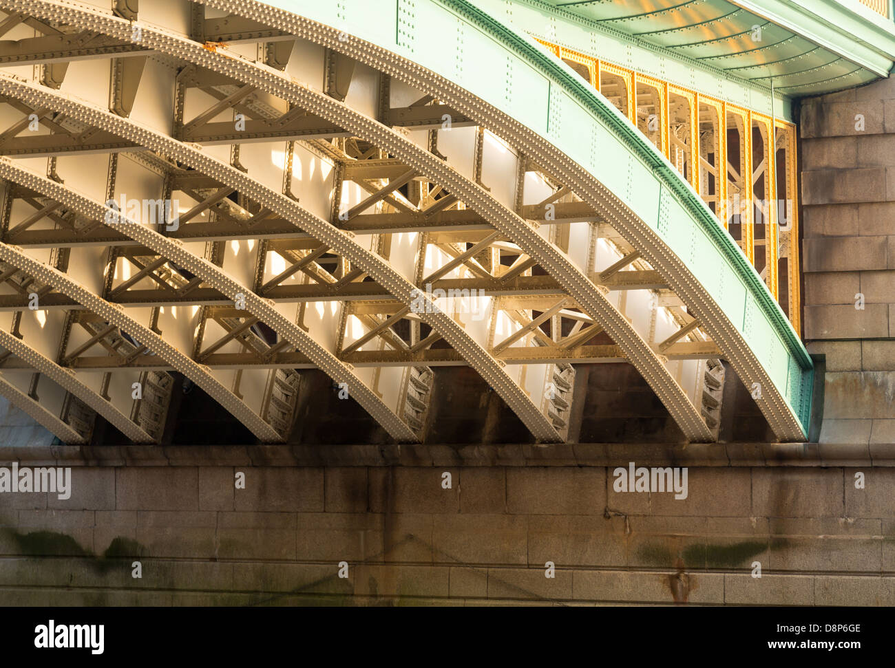 Girders supporting Southwark Bridge across the Thames river in London with setting sun lighting the painted ironwork Stock Photo