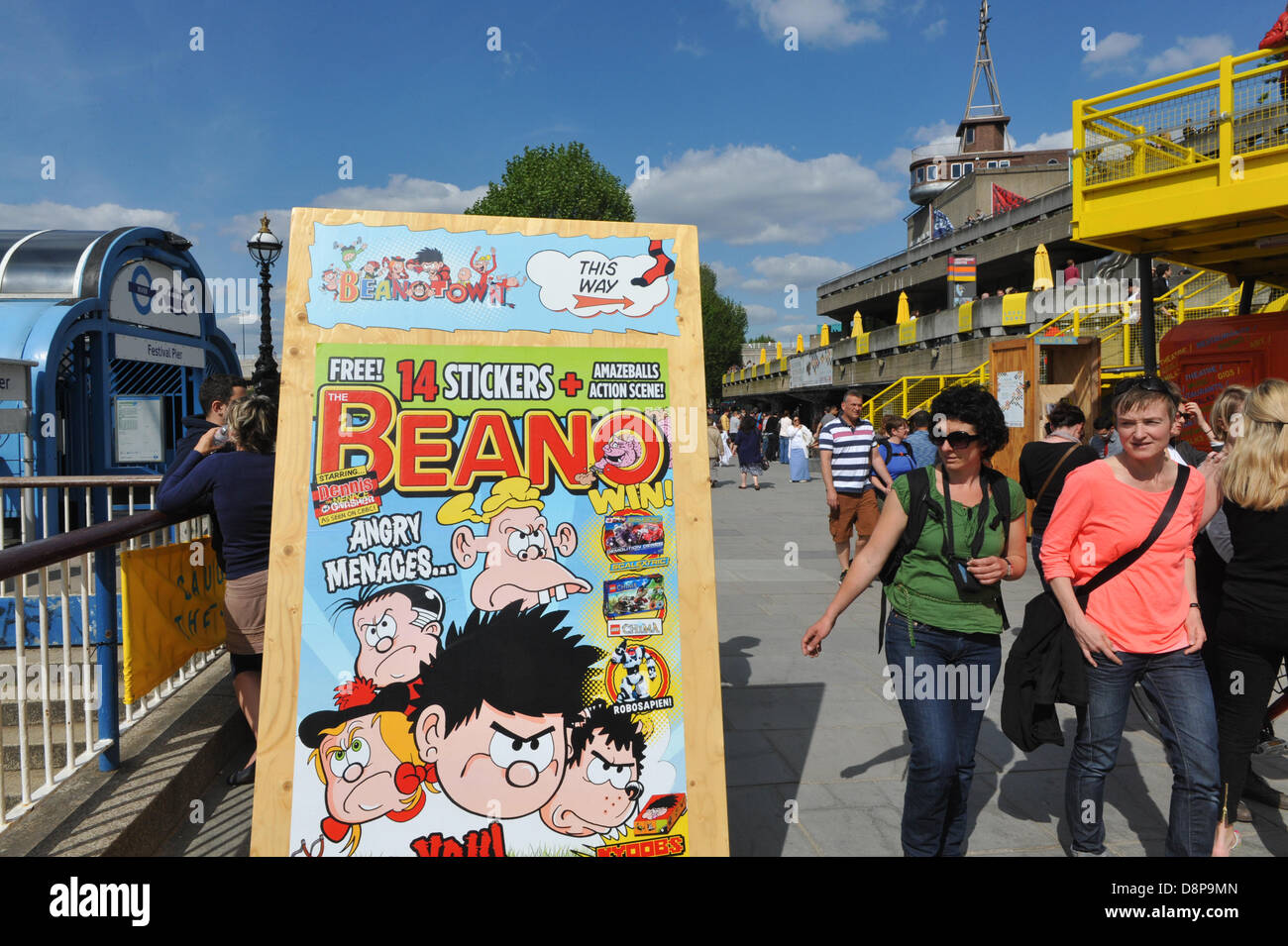 Southbank Centre, London, UK. 2nd June 2013. People walk past a poster for Beanotown, a celebration of the children's comic. Beanotown in the Southbank Centre in London, 'Beanotown is the home of Dennis the Menace and Gnasher, The Bash Street Kids, Minnie the Minx, Roger the Dodger, plus all the other comic strip superstars from The Beano'. Beanotown is on from 31st May to 8th September. Credit:  Matthew Chattle/Alamy Live News Stock Photo