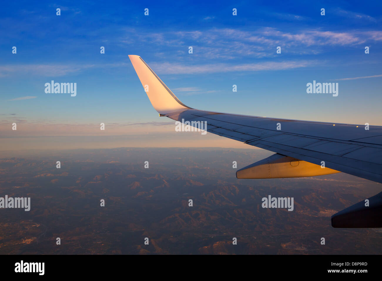 Airplane jet wing at sunset with golden light sun reflection Stock