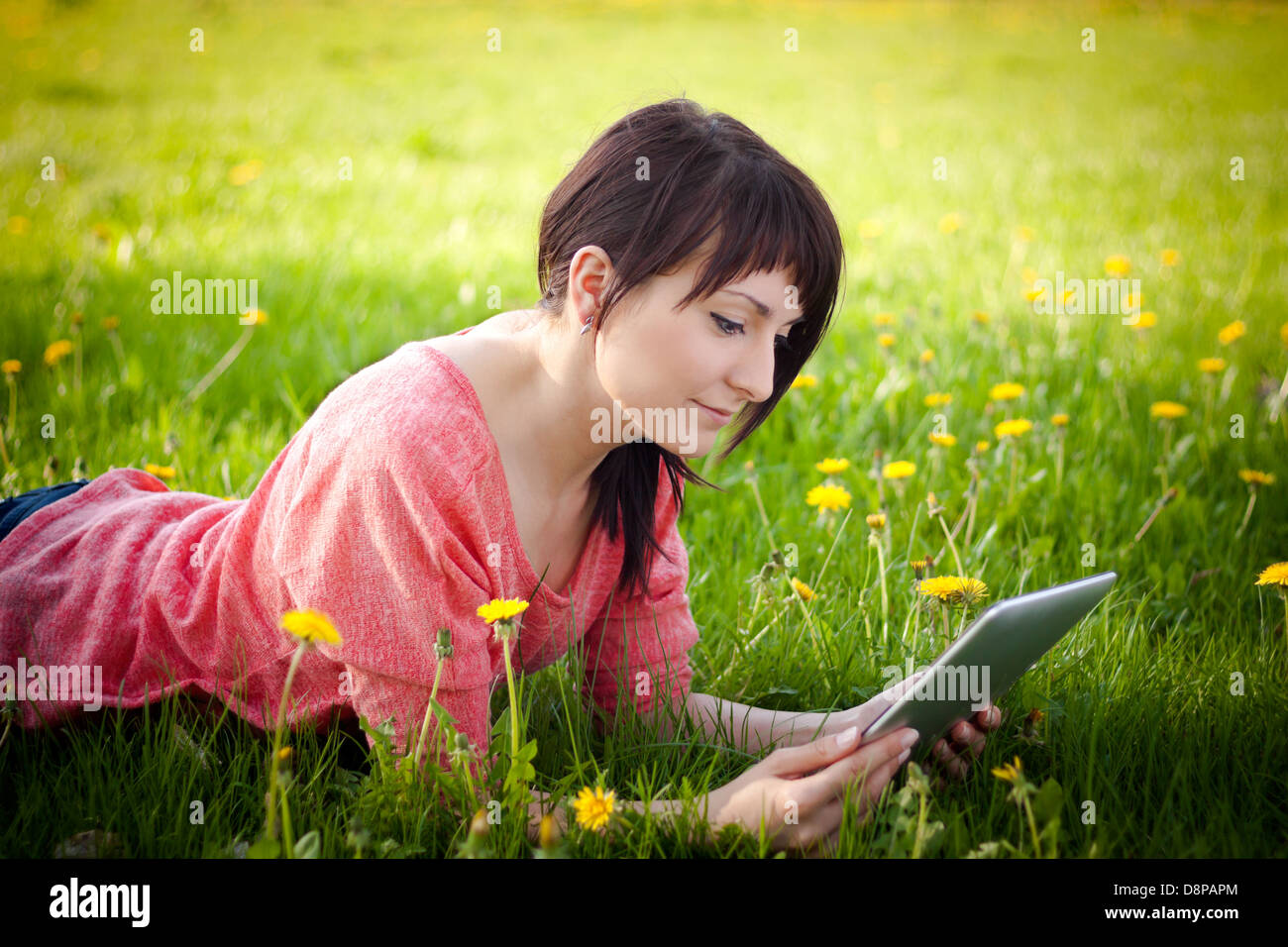 Young woman using tablet outdoor laying on grass Stock Photo