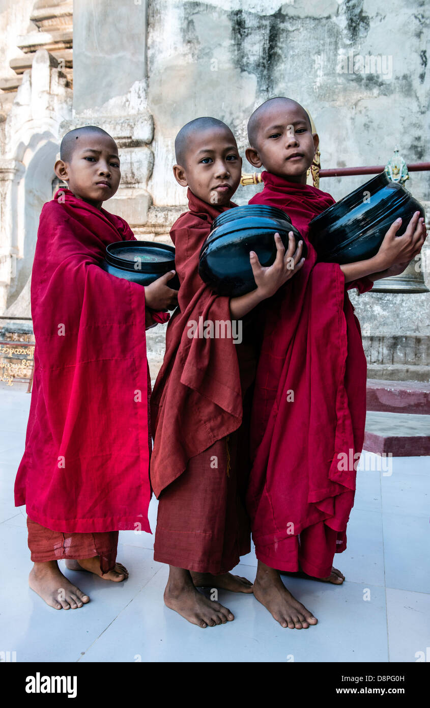 Novice Buddhist monks collecting alms bowls of food in the morning from villagers near Bagan Burma Myanmar Stock Photo