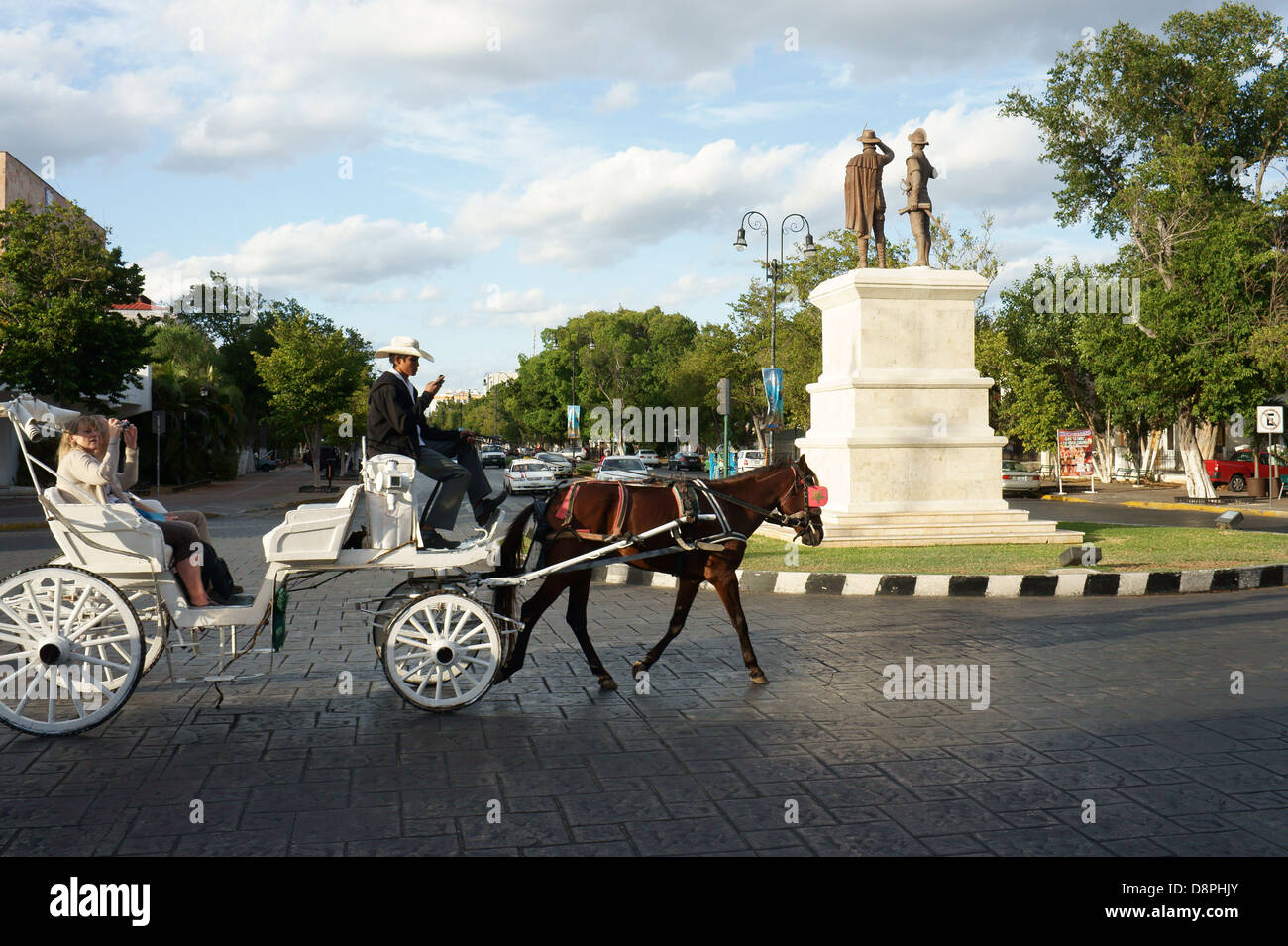 Tourists riding in a horse drawn carriage or calesa on Paseo de Montejo, Merida, Yucatan, Mexico Stock Photo