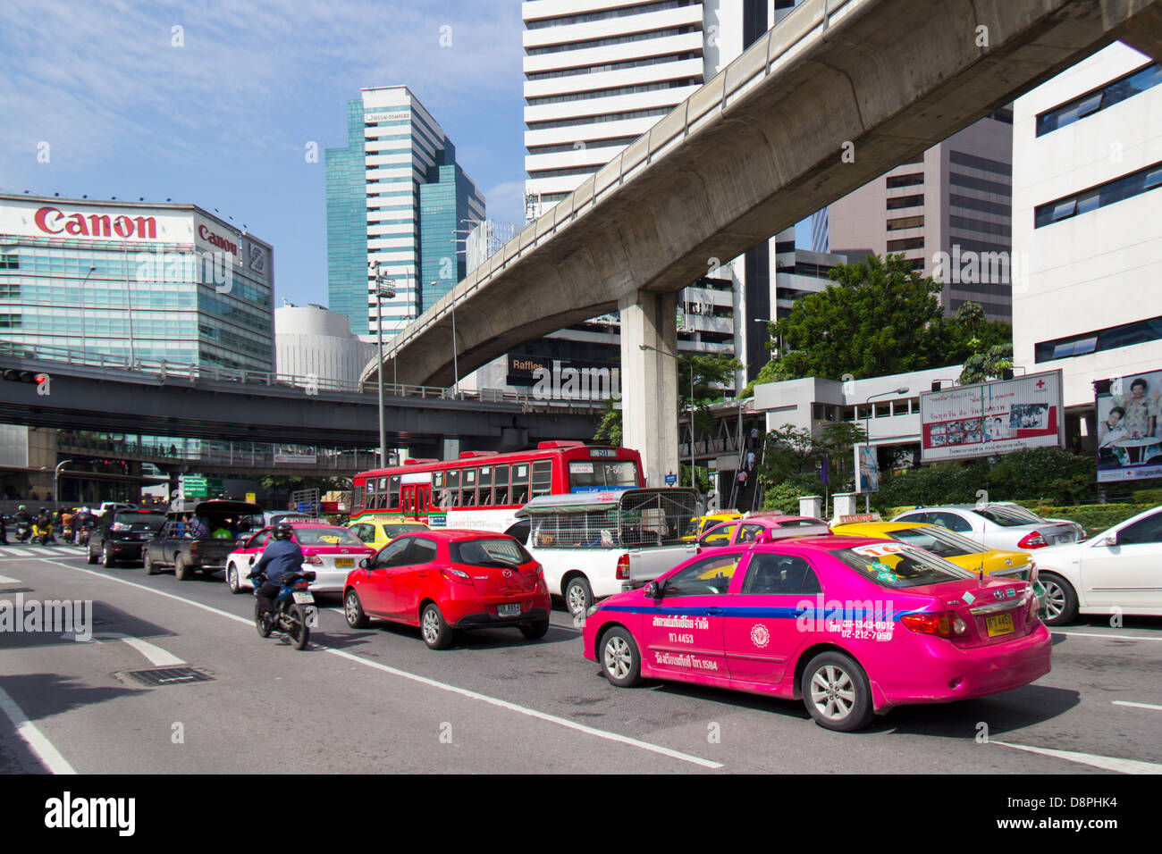 Bangkok traffic on Ratchadamri Road heading towards Silom Road with skytrain track, flyover and office buidlings in view Stock Photo