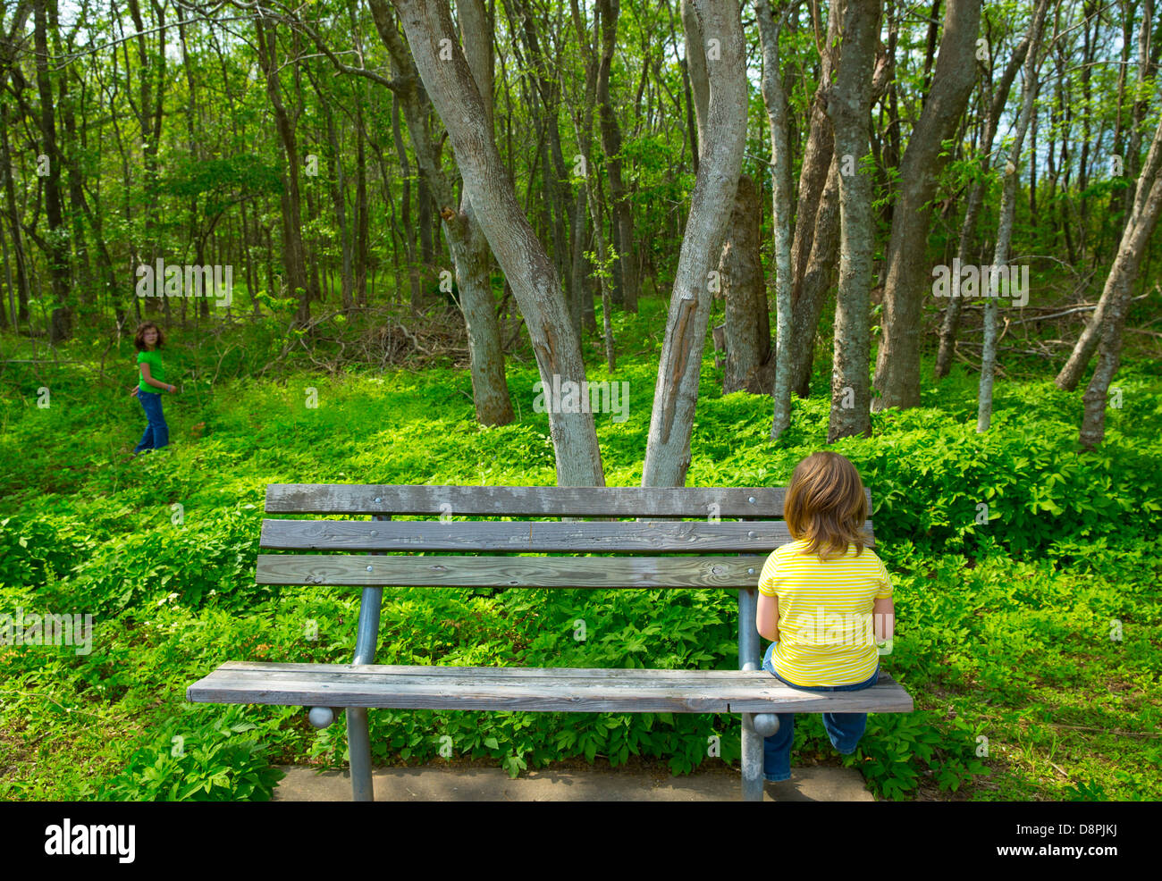 Lonely children sad looking the forest girl sitting at the park bench Stock Photo