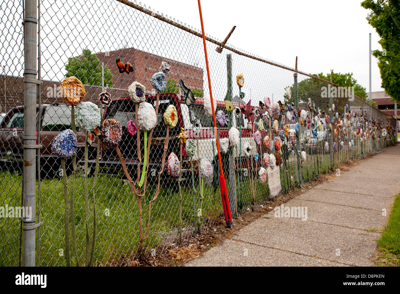 Fabric Flowers Decorating A Chain Link Fence Surrounding Junk Cars