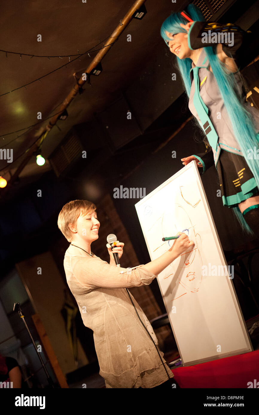 Young woman poses for an artist in cosplay / japanse/manga/ anime dress onstage in a Dr Sketchy life drawing event Stock Photo