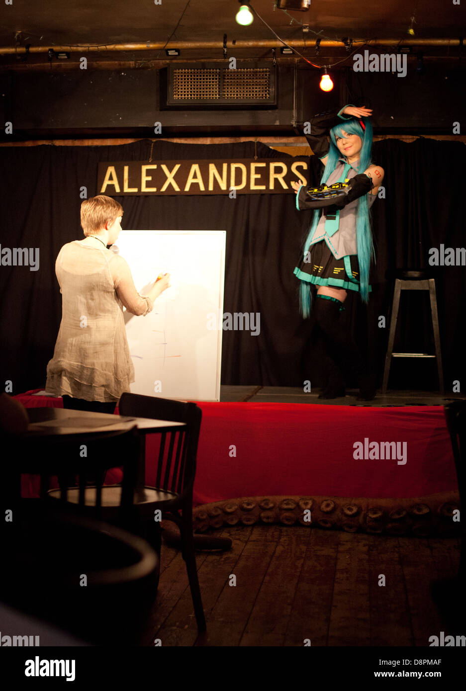 Woman draws an anime / manga / cosplay performer onstage at a Dr Sketchy burlesque life drawing event Stock Photo