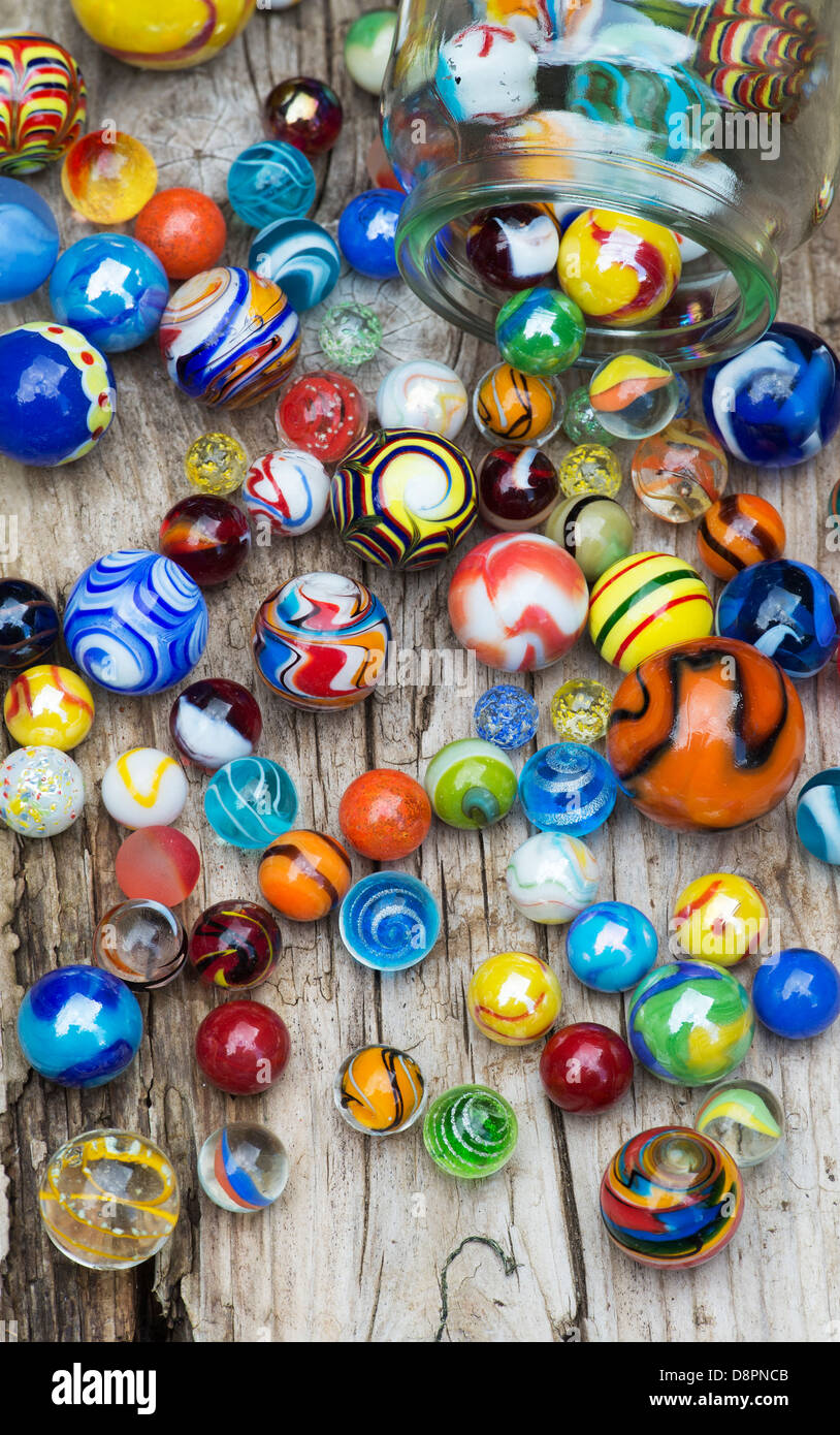 Colourful marbles and glass jar on old wood Stock Photo