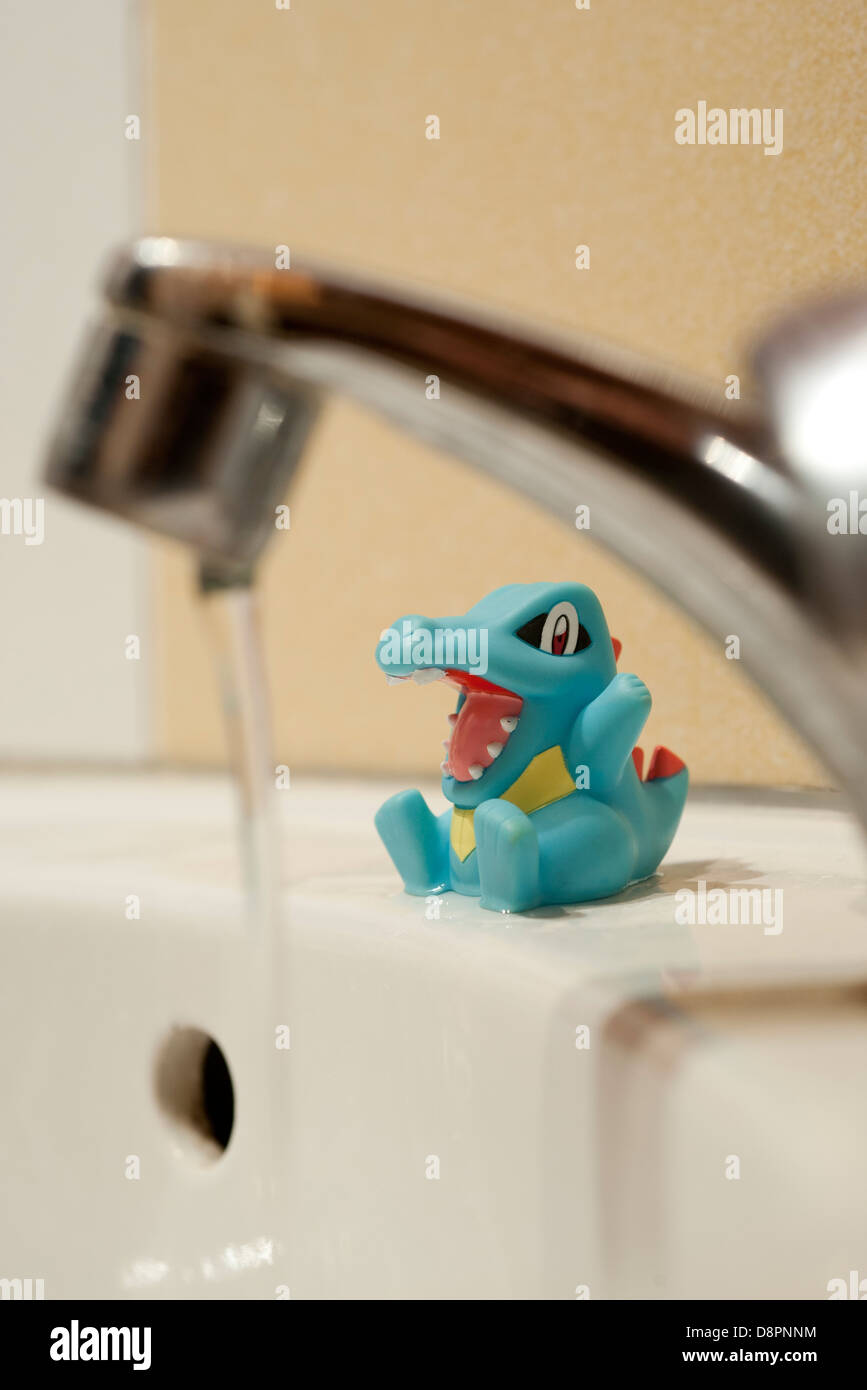 Child's toy sitting on side of bathtub, water running in foreground Stock Photo