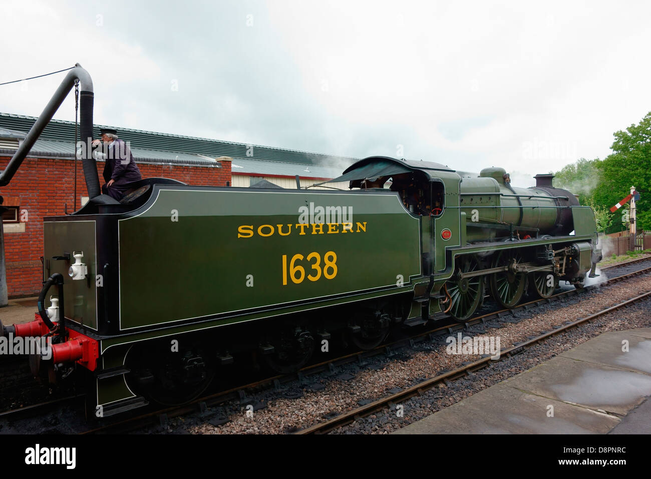 Man filling up water tank of a steam train engine Stock Photo