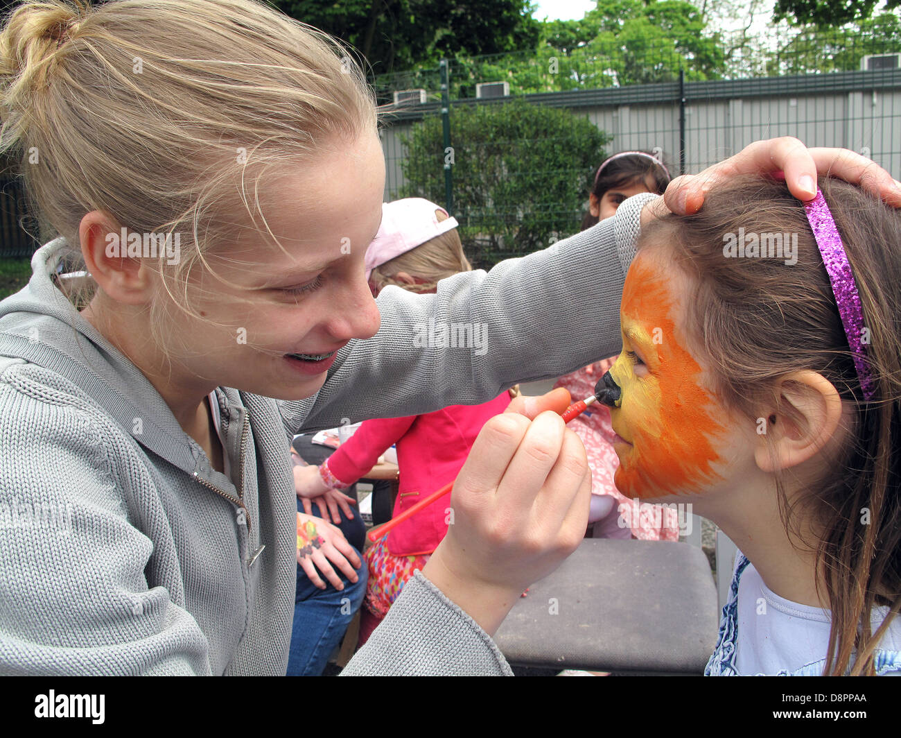 Teenage girl applies face paint to a preteen girl in the UK Stock Photo