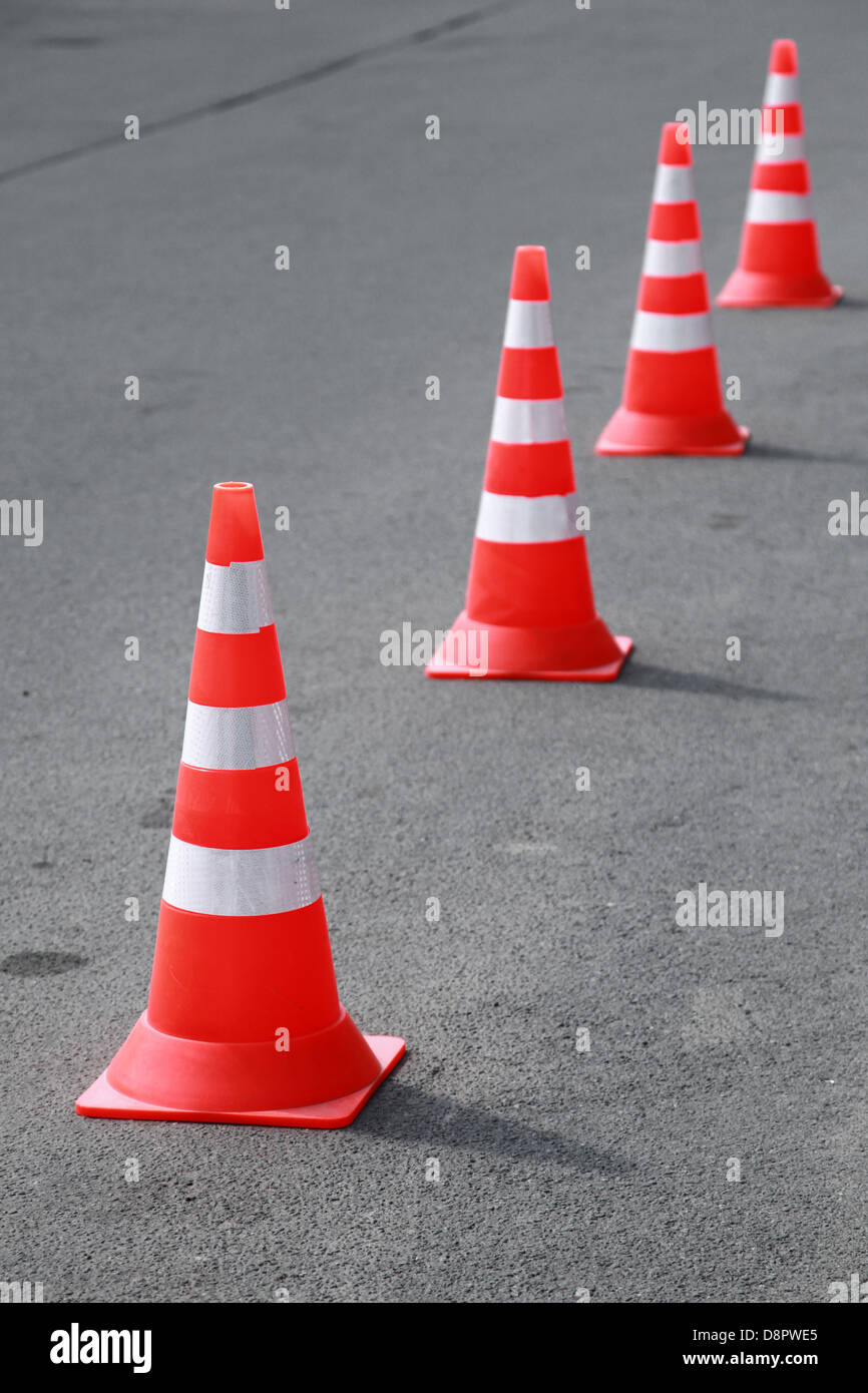 Four striped orange cones stand on gray asphalt road Stock Photo