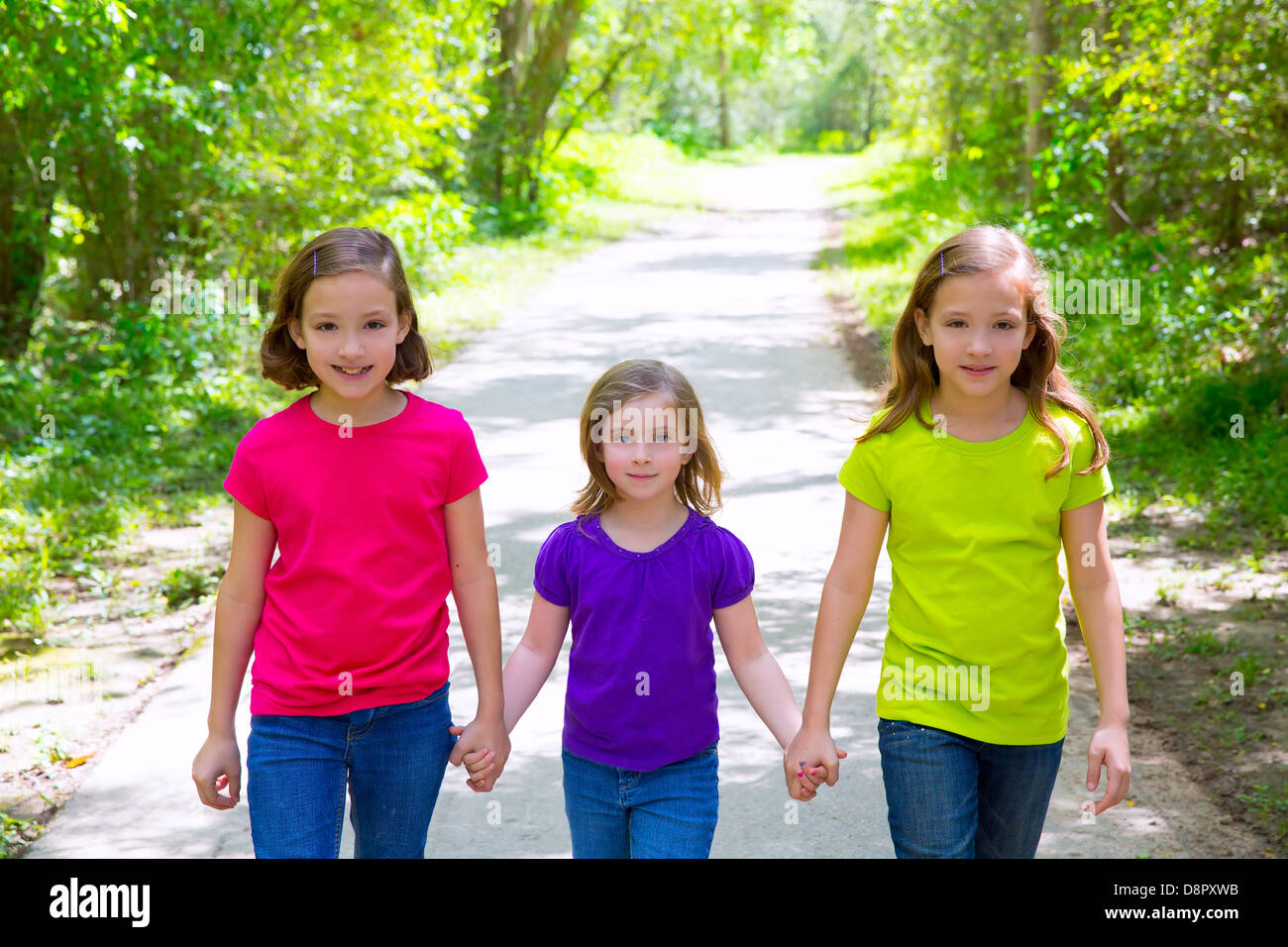 Friends and sister girls walking outdoor in forest track excursion Stock Photo