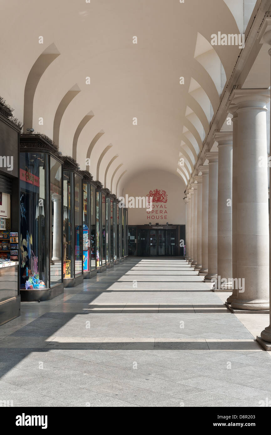 sunlit walkway under and trough shop lined fronts and columns to entrance Royal Opera House Stock Photo