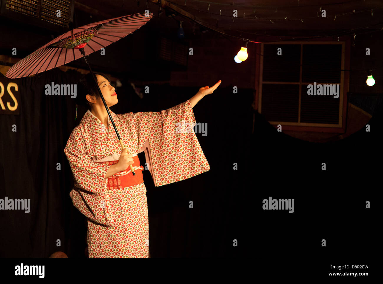 Young Japanese woman performs a traditional Japanese dance with parasol