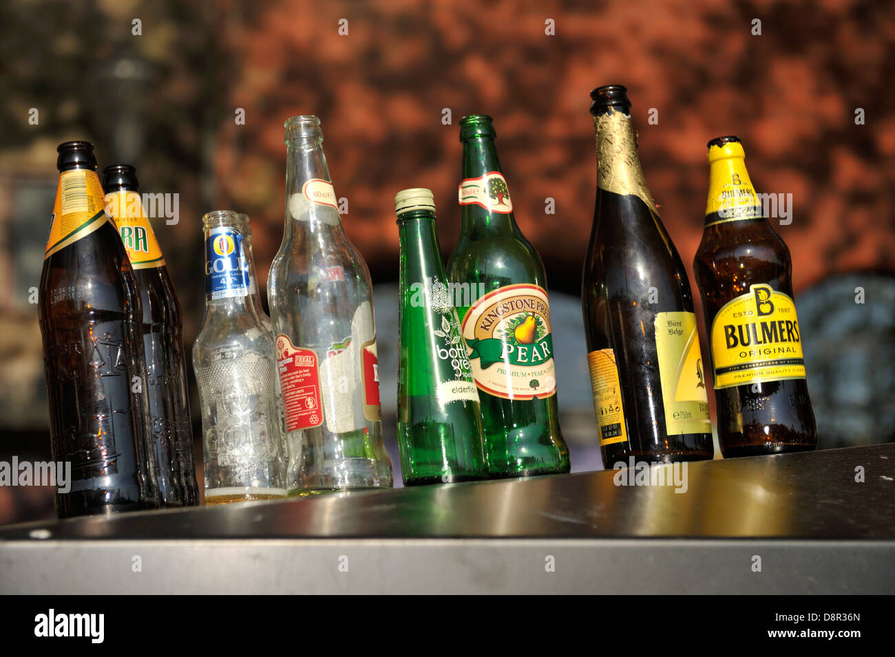 Empty drinks bottles lined up on top of recycling container outside pub Stock Photo