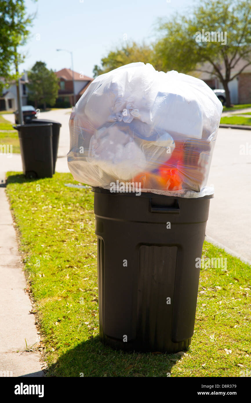 Trash bin dustbin full of excess garbage on street lawn Stock Photo