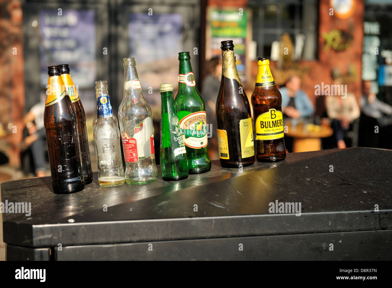 Empty drinks bottles lined up on top of recycling container outside pub Stock Photo