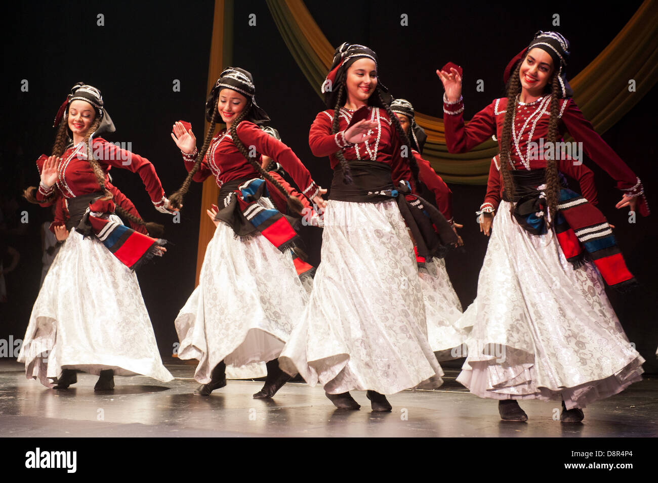 children dressed with traditional costumes dancing a folklore dance show on stage Stock