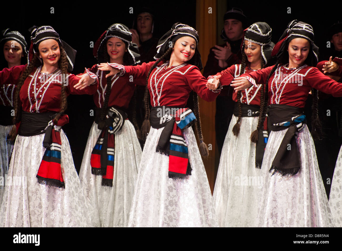 children dressed with traditional costumes dancing a folklore dance show on stage Stock