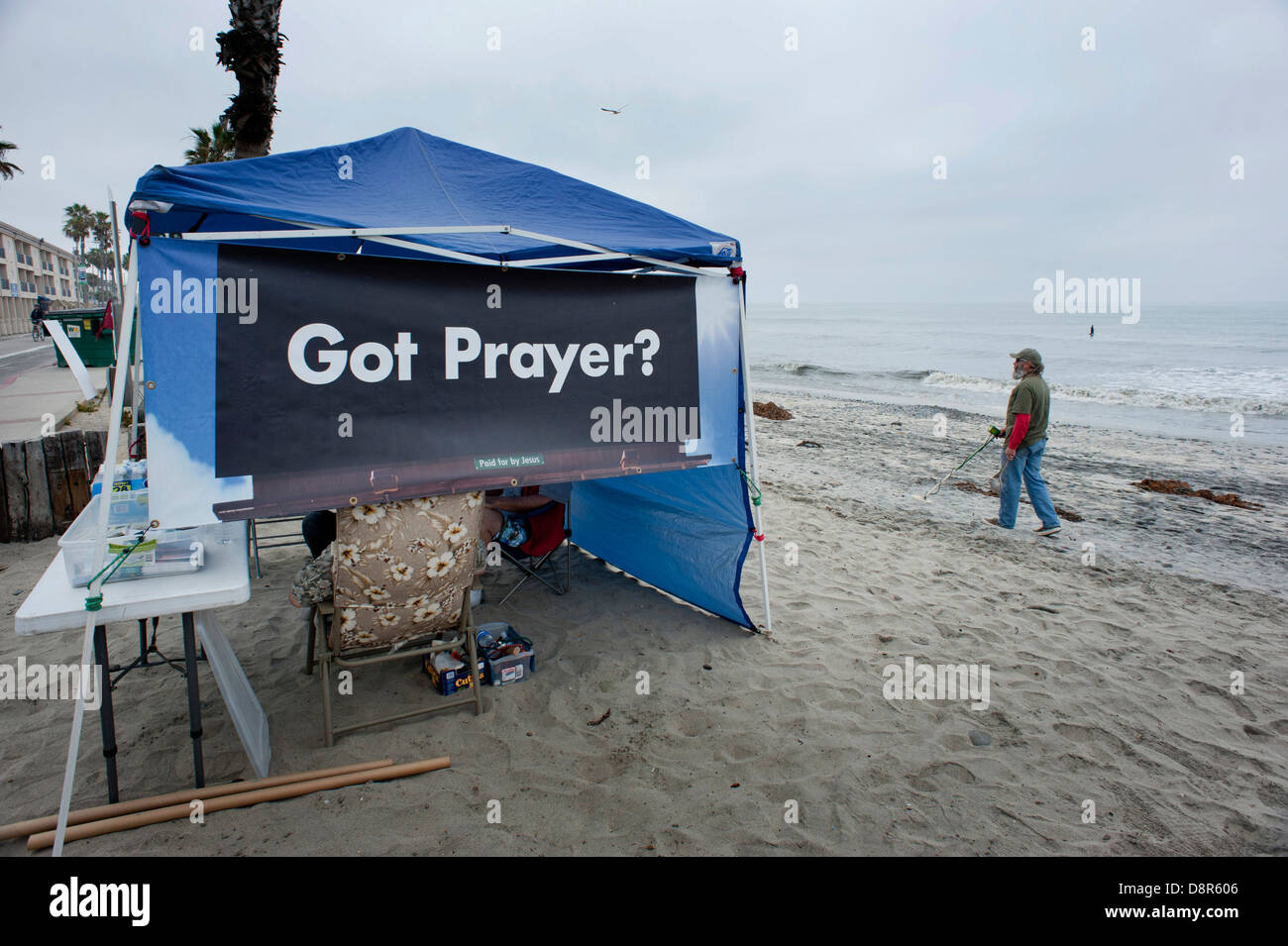 A prayer tent on the beach is ignored by a man with a metal detector. Stock Photo