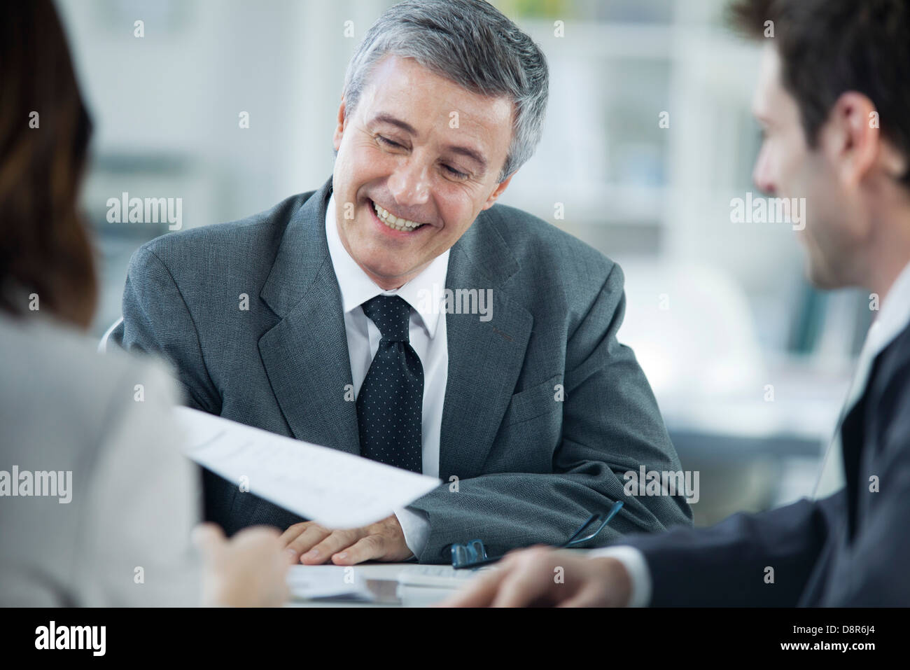 Businessman smiling in meeting with colleagues Stock Photo