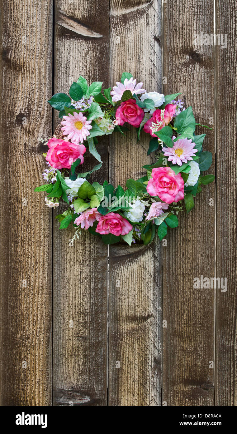 Floral wreath hanging on rustic wooden fence Stock Photo