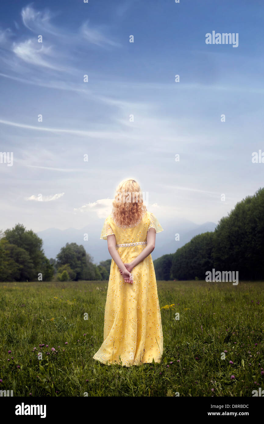 a blond woman in a yellow dress on a meadow Stock Photo