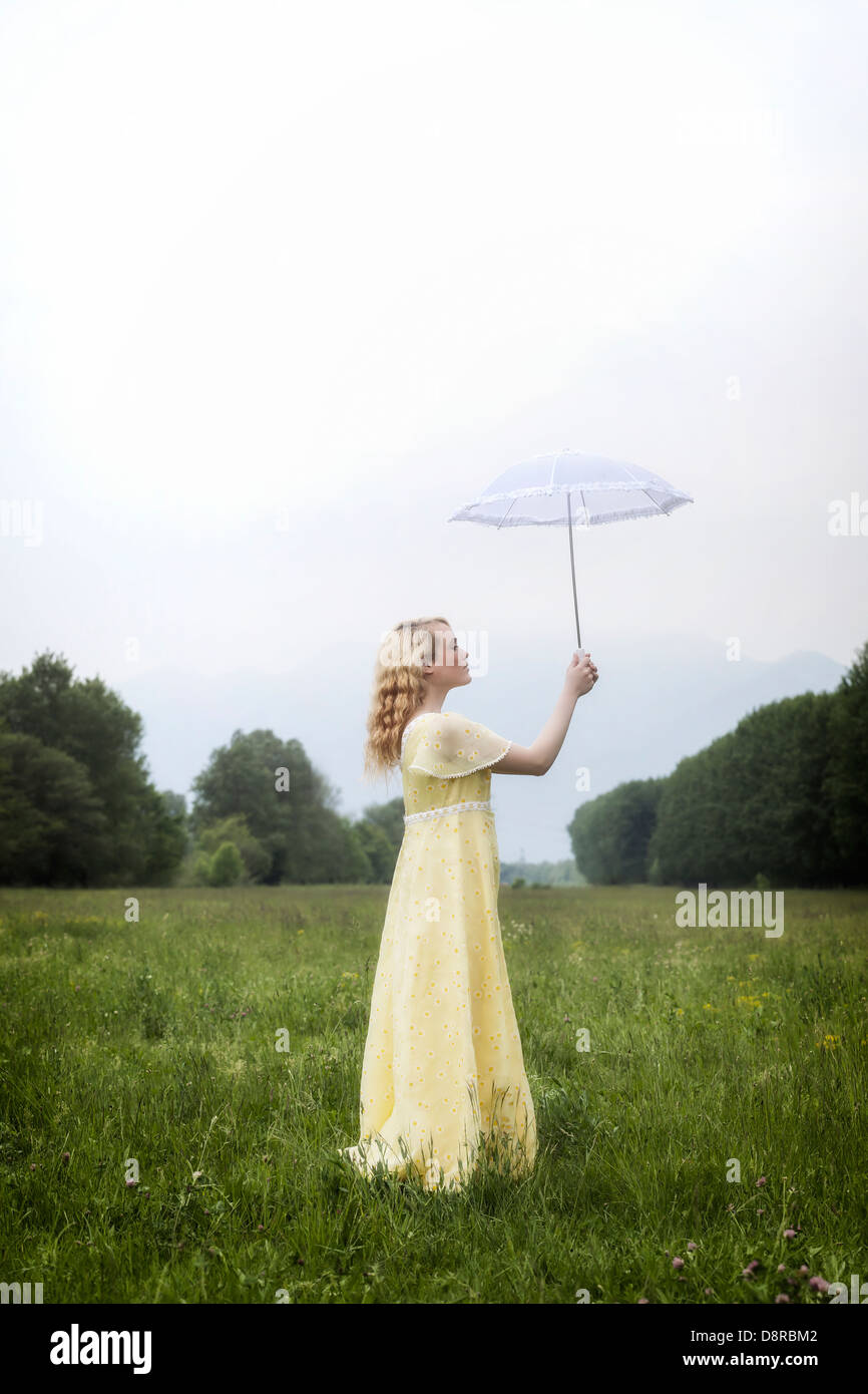 a girl in a yellow dress is standing on a meadow with a parasol Stock ...