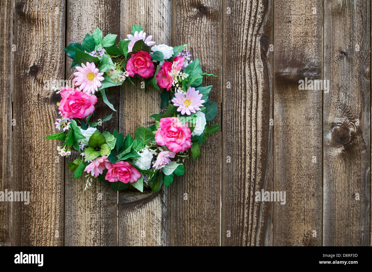 Flower wreath hanging on rustic wooden fence Stock Photo