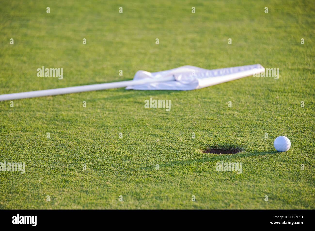 ball and flag on green of golf course Stock Photo
