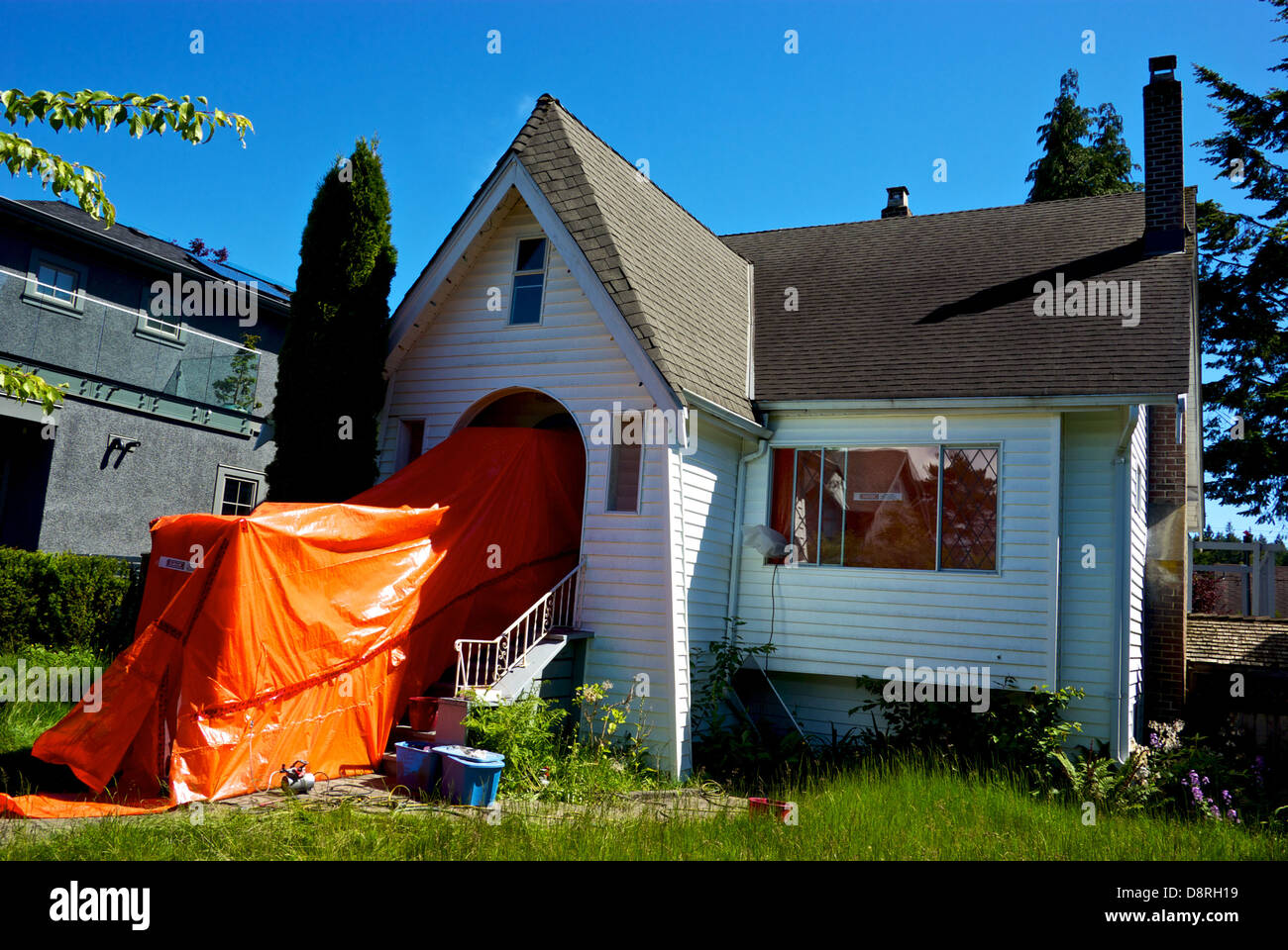 Heavy duty orange plastic tarpaulin sealed entrance Vancouver house awaits asbestos hazardous material removal before demolition Stock Photo