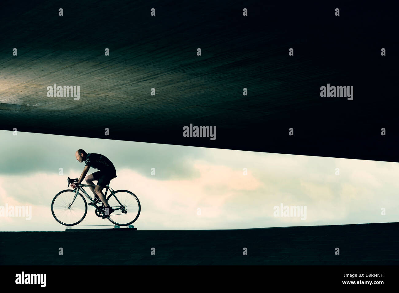 Cyclist on racing cycle under a bridge in an abstract environment. Stock Photo