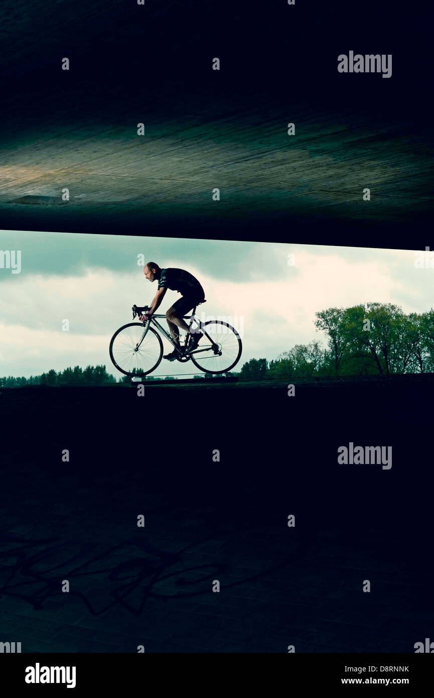 Cyclist on racing cycle under a bridge in an abstract environment. Stock Photo