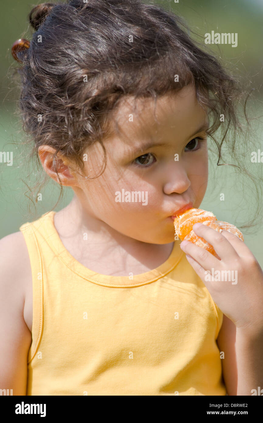 little girl eating tangerine Stock Photo Alamy