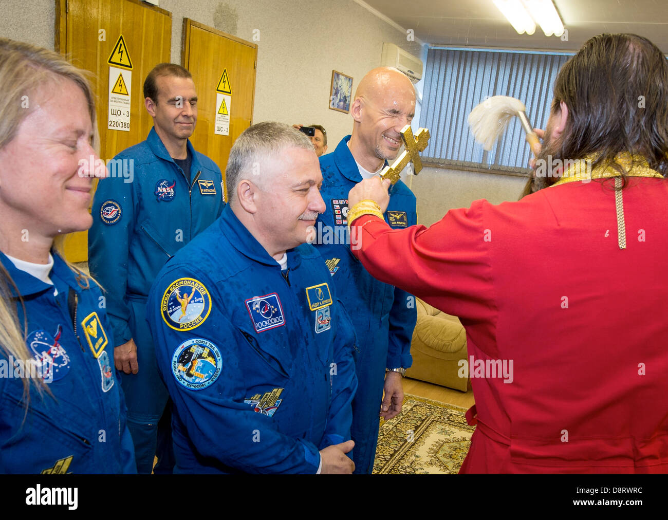 Expedition 36/37 Flight Engineer Karen Nyberg of NASA, left, Soyuz Commander Fyodor Yurchikhin of the Russian Federal Space Agency, center, and Flight Engineer Luca Parmitano of the European Space Agency, receive a traditional blessing from an Orthodox Priest prior to the three crew members departing the Cosmonaut Hotel for suit up and launch onboard a Soyuz to the International Space Station May 28, 2013 in Baikonur, Kazakhstan. Stock Photo