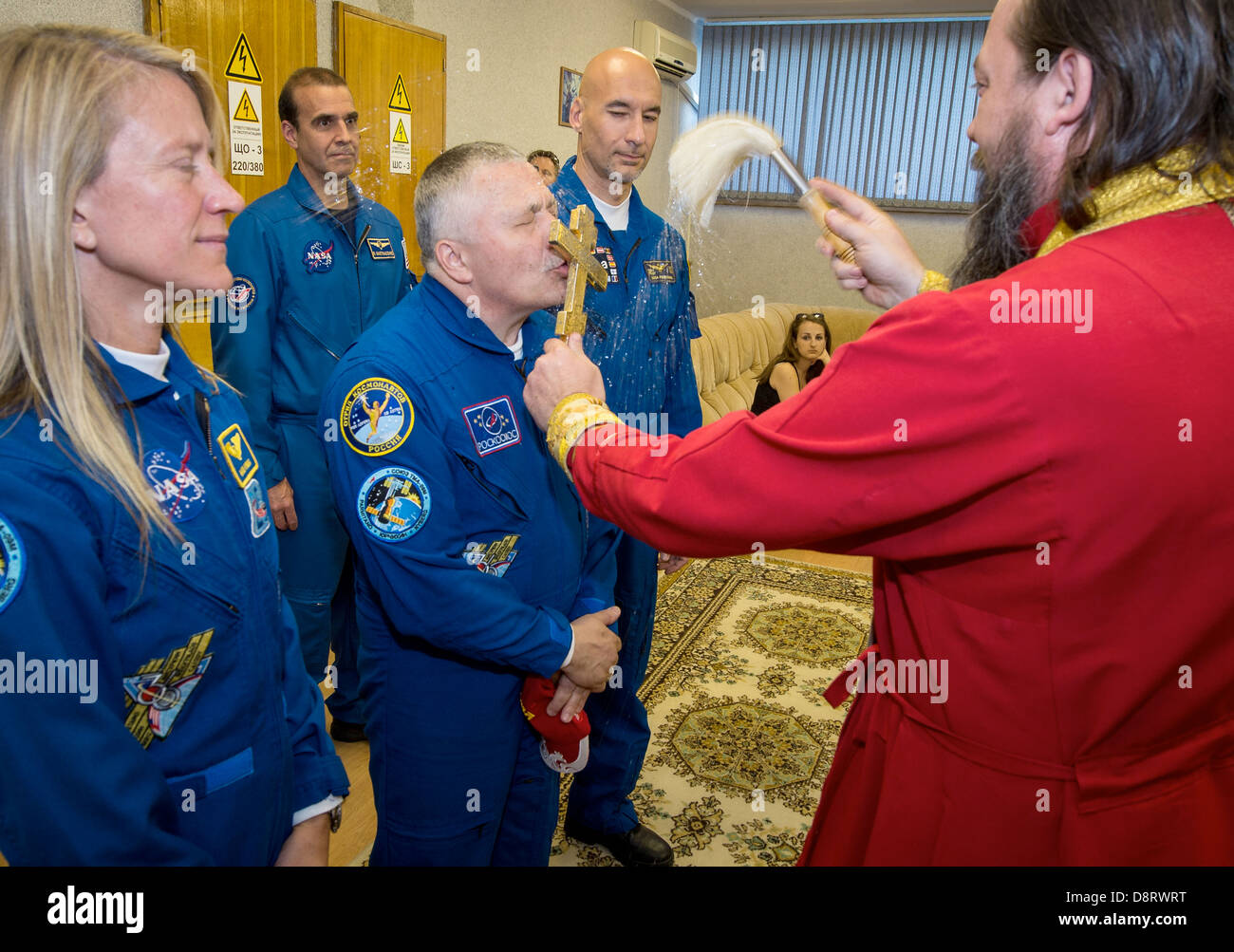 Expedition 36/37 Flight Engineer Karen Nyberg of NASA, left, Soyuz Commander Fyodor Yurchikhin of the Russian Federal Space Agency, center, and Flight Engineer Luca Parmitano of the European Space Agency, receive a traditional blessing from an Orthodox Priest prior to the three crew members departing the Cosmonaut Hotel for suit up and launch onboard a Soyuz to the International Space Station May 28, 2013 in Baikonur Kazakhstan. Stock Photo