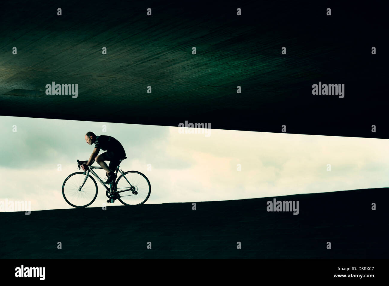 Cyclist on racing cycle under a bridge in an abstract environment. Stock Photo