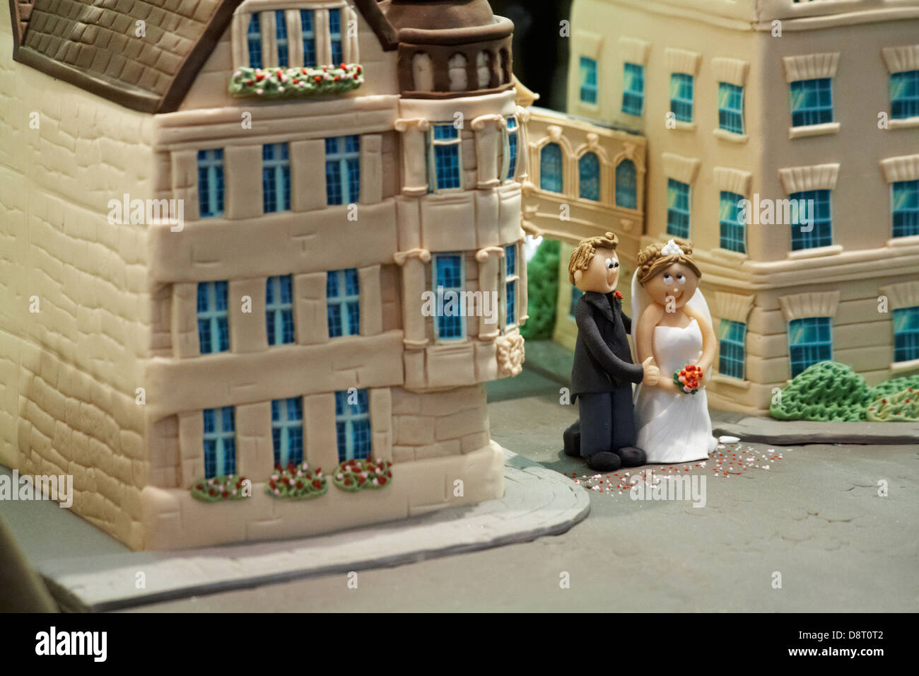 Looking through window of cake shop at decorated cake of bride and groom standing in front of bridge of Sighs at Oxford, Oxfordshire UK  in May Stock Photo